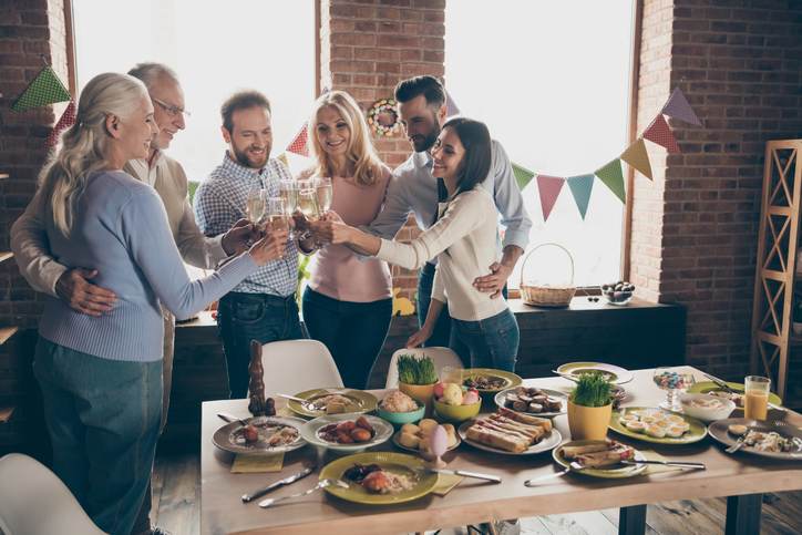 Close up of gathered relatives in decorated house dinner table with glasses golden beverage in hands family best friends wishing all great big large company