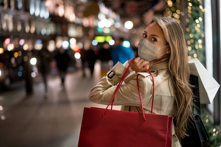 Happy woman Christmas shopping wearing a facemask