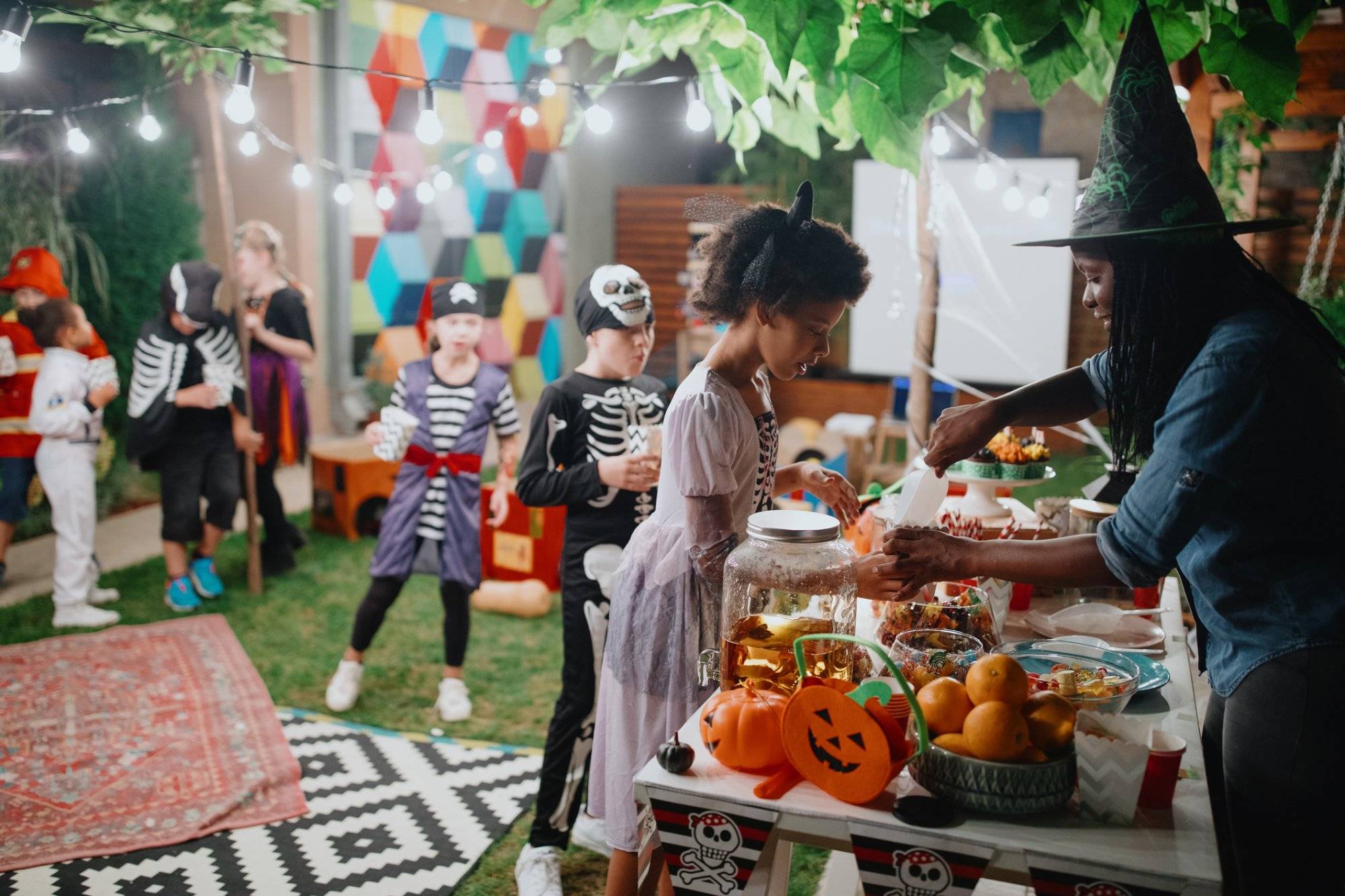 Parent serving candy and popcorn to her kids and their friends at backyard movie night Parent serving candy and popcorn to her kids and their friends at backyard movie night