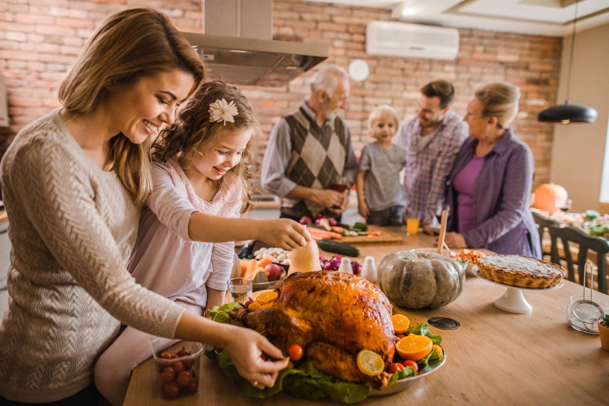 Happy mother and daughter preparing roasted turkey for Thanksgiving dinner. Happy mother and daughter preparing roasted turkey for Thanksgiving dinner.