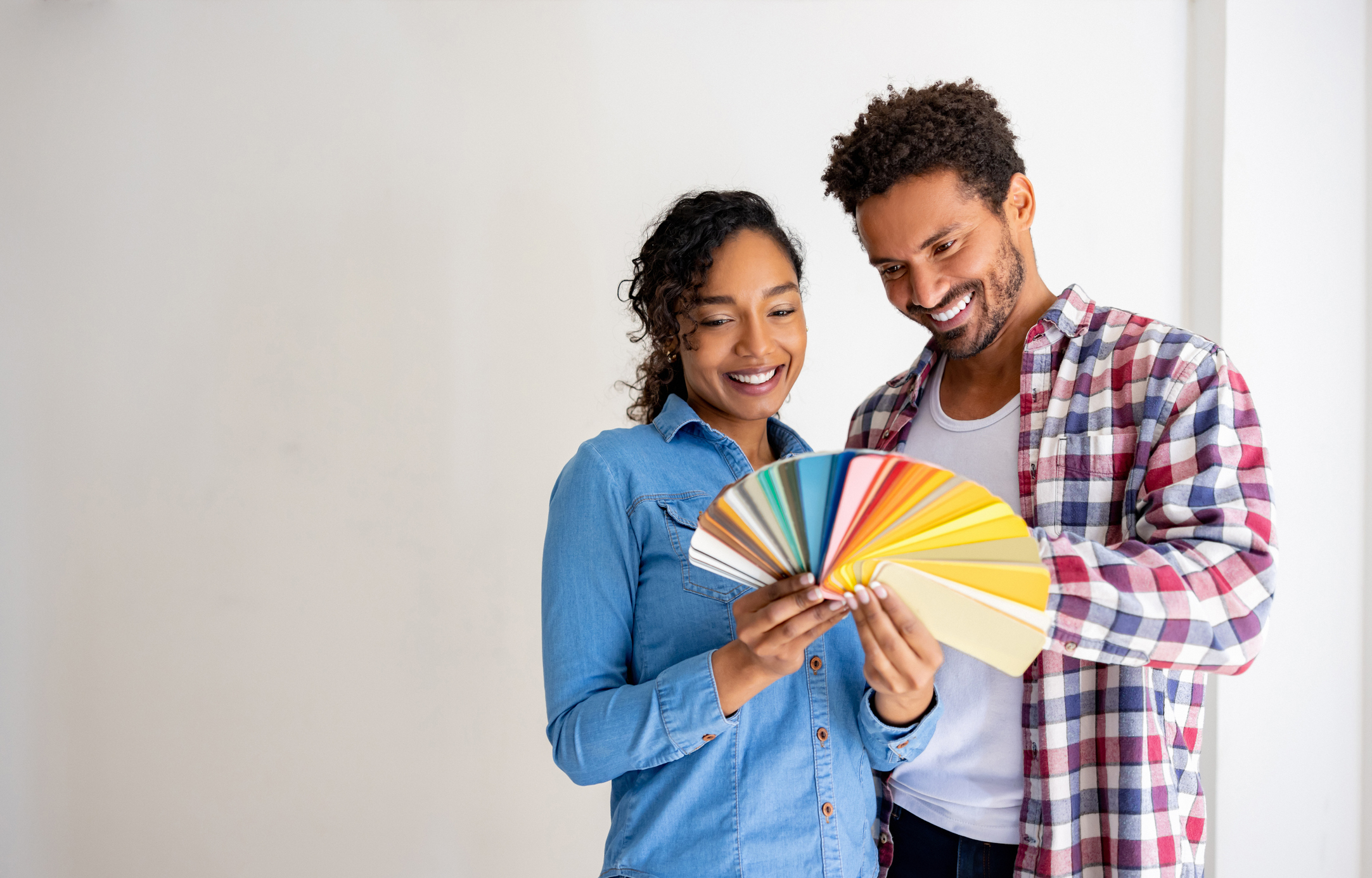 Happy Latin American couple choosing a color for the walls while remodeling their house